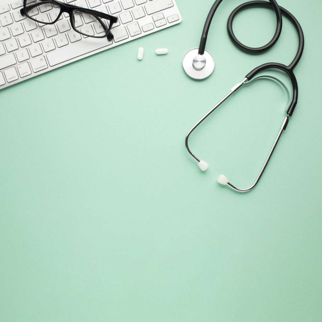 white-pills-stethoscope-near-spectacles-wireless-keyboard-backdrop